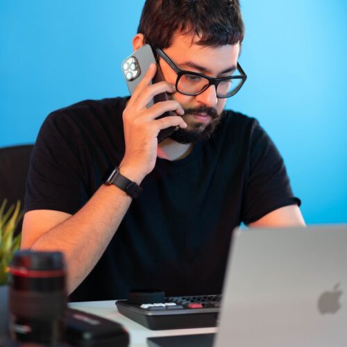 a man sitting at a desk talking on a cell phone
